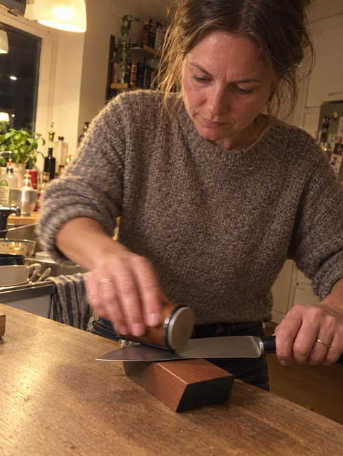 Illustrativt billede: kvinde sliber kniv i sit køkken